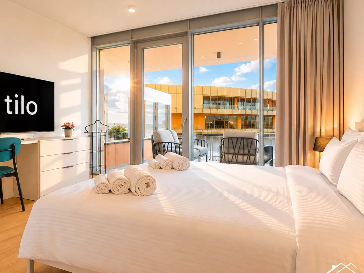 Beds made hotel-style, towels rolled, screen with the house guide